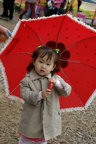 지난달 31일 영취산진달래 축제 현장에서 부모를 따라온 아이가 비가오자 우산을 들고 있다.